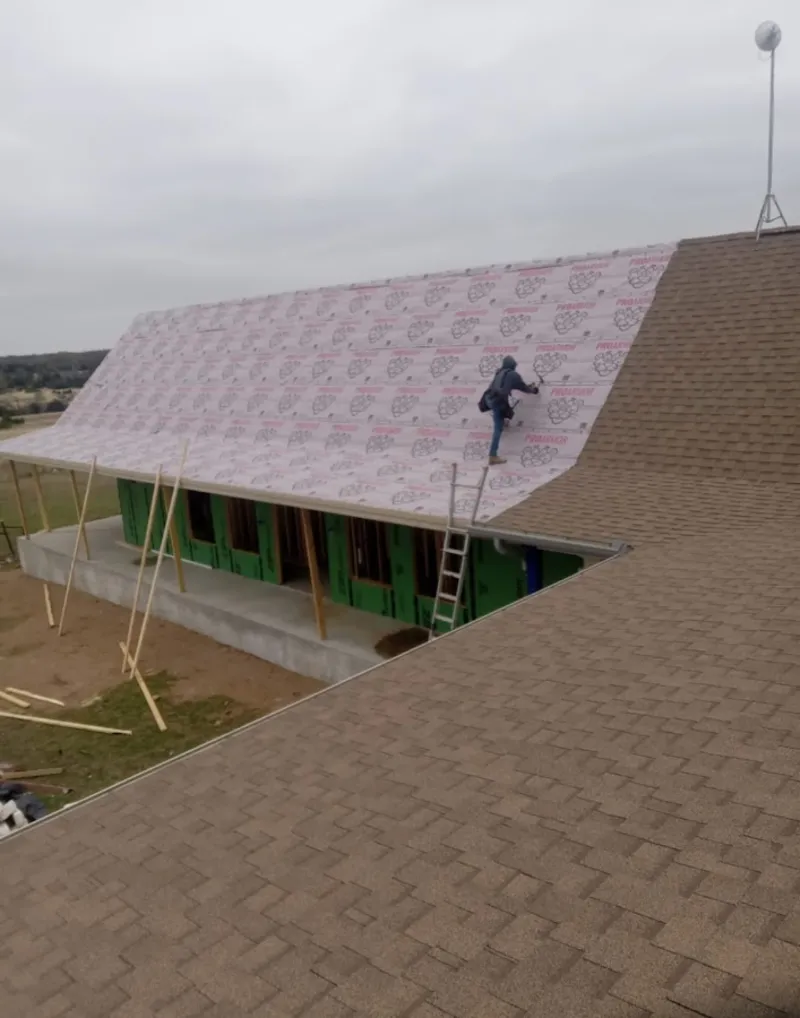 Worker preparing underlayment for a metal roof installation in Friendswood